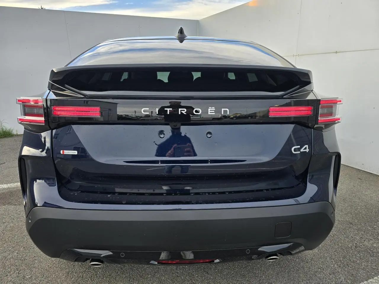 Vue arrière d'une Citroën C4 III hybride bleu eclipse avec toit noir et feux arrière LED distinctifs.