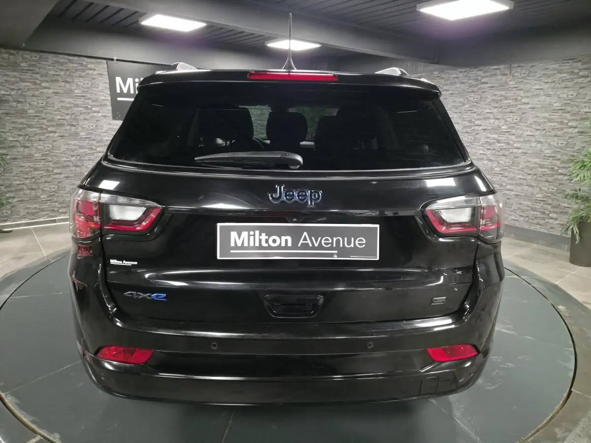 Vue arrière d'un Jeep Compass noir avec logo 4xe et toit noir dans un showroom intérieur.