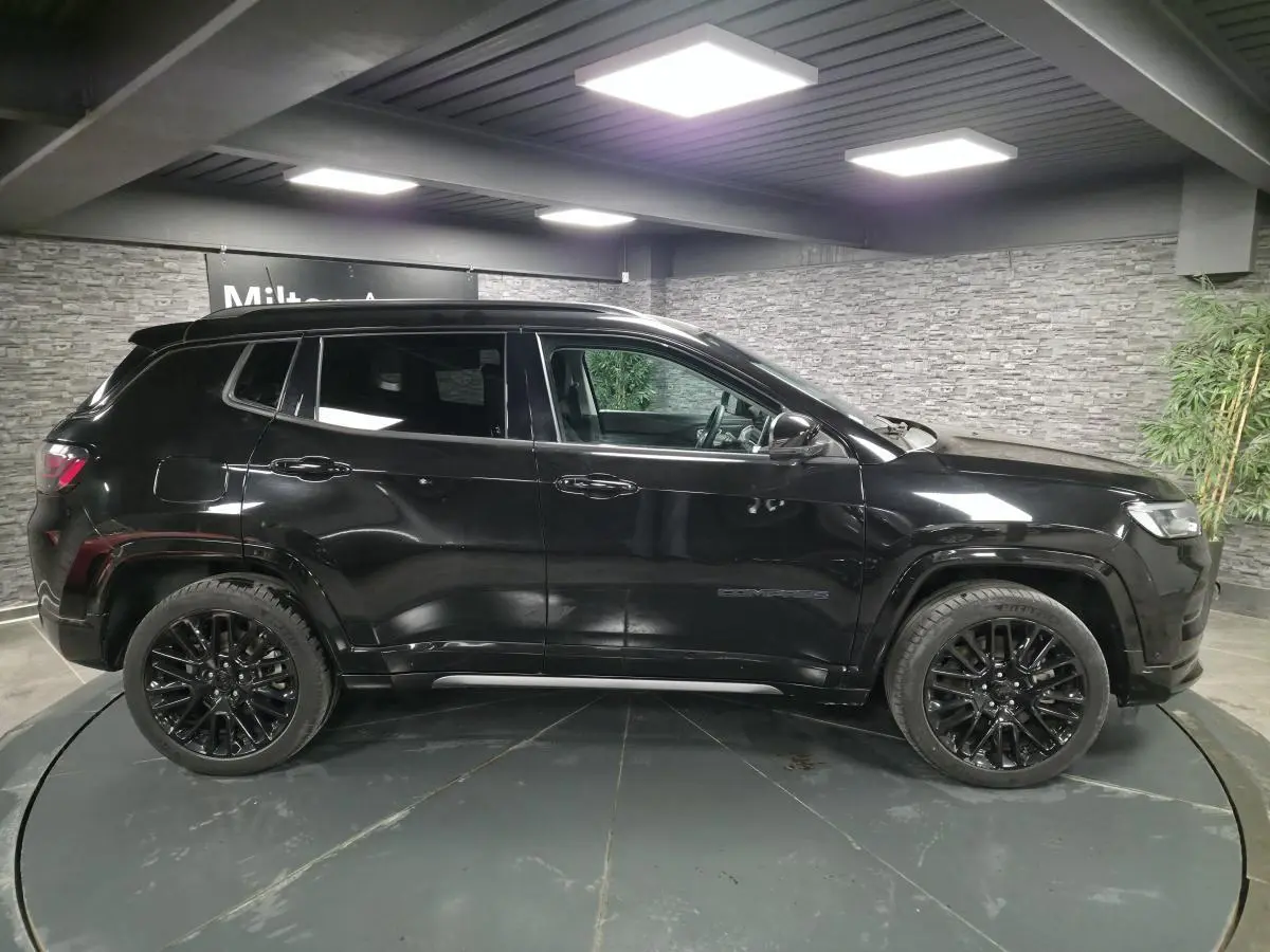 Jeep Compass 2022 noir vue profil côté gauche, avec jantes alliage noires et toit noir en intérieur showroom.