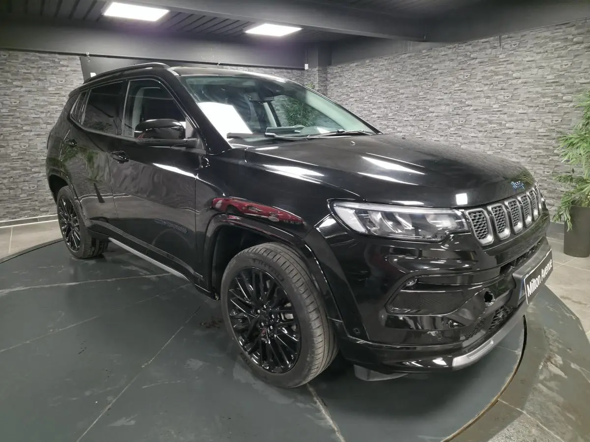 Jeep Compass noir en 3/4 avant droit, avec jantes alliage noires et toit noir dans un showroom intérieur.