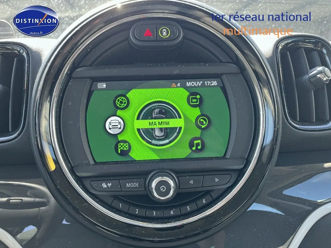 Vue rapprochée de l’écran central rond du tableau de bord d’une MINI Countryman avec interface verte et commandes intégrées.