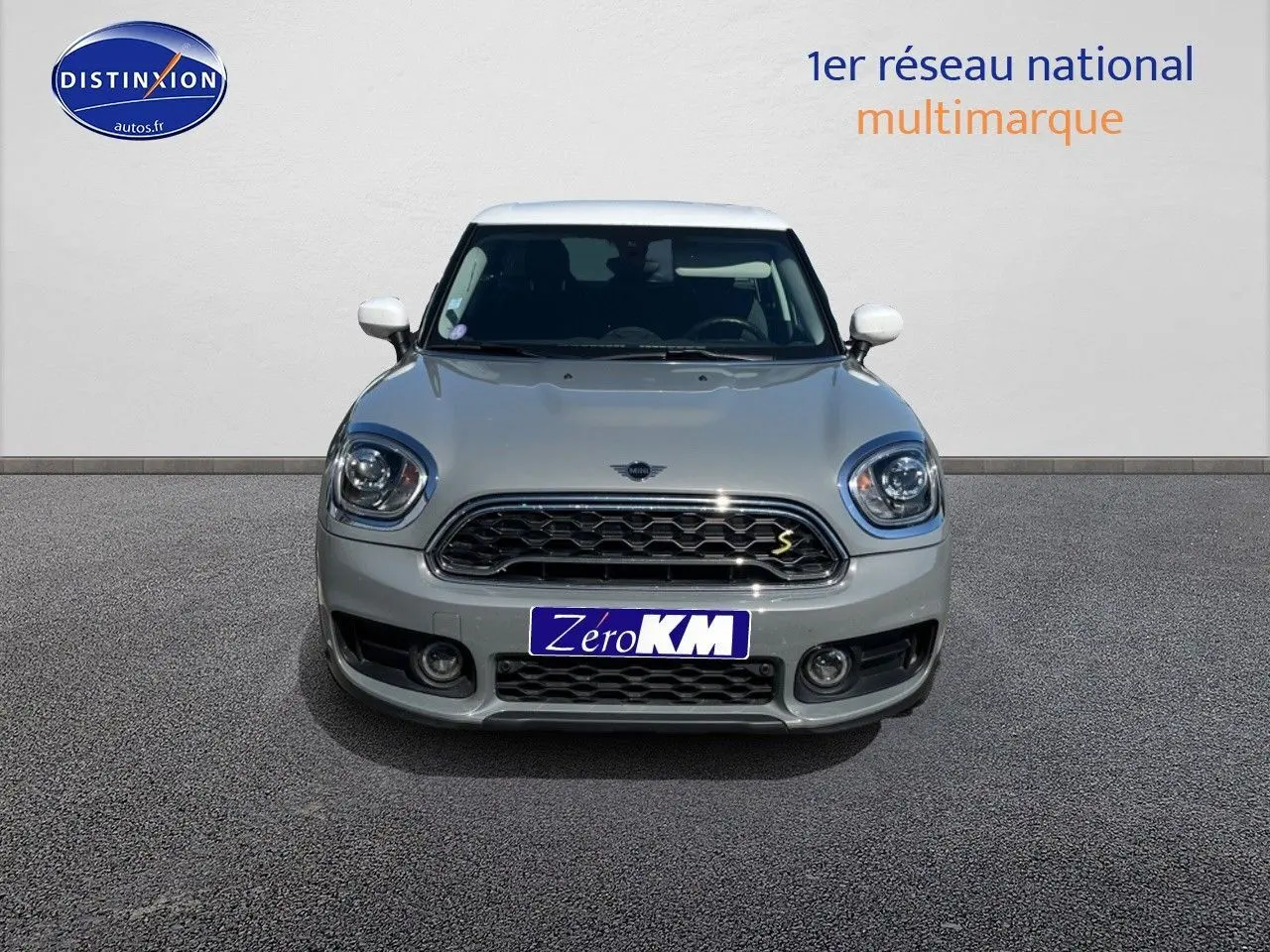 Vue avant d'une MINI Countryman hybride rechargeable Moonwalk Grey avec toit et rétroviseurs blancs, calandre chromée.