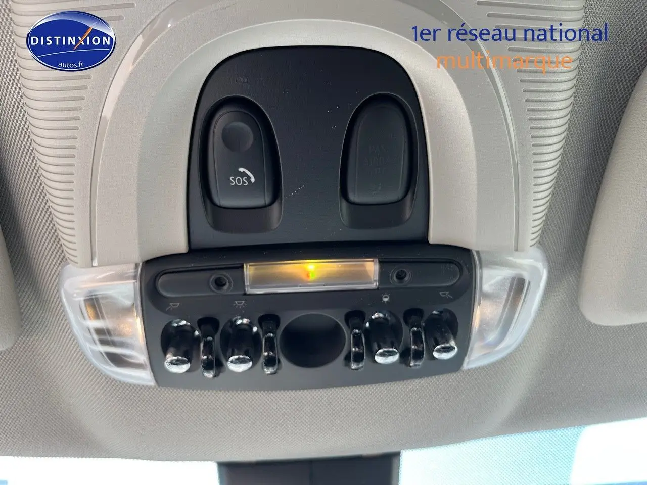 Vue en gros plan du plafonnier avec interrupteurs chromés et bouton SOS dans l'habitacle clair d'une MINI Countryman Moonwalk Grey.
