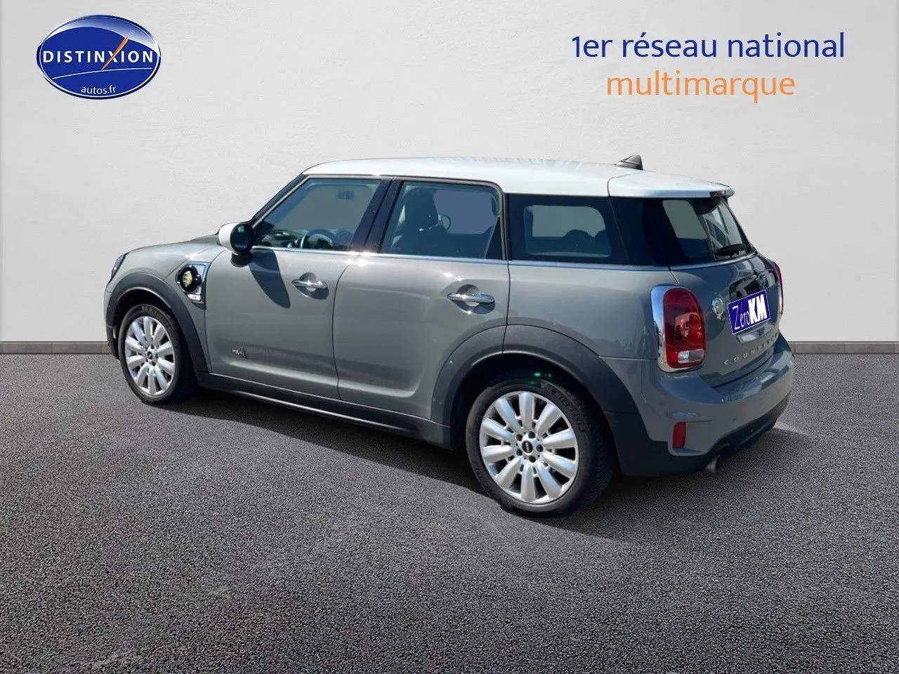 Vue 3/4 arrière droite d'une MINI Countryman hybride gris Moonwalk avec toit et rétroviseurs blancs et jantes alu 18 pouces.