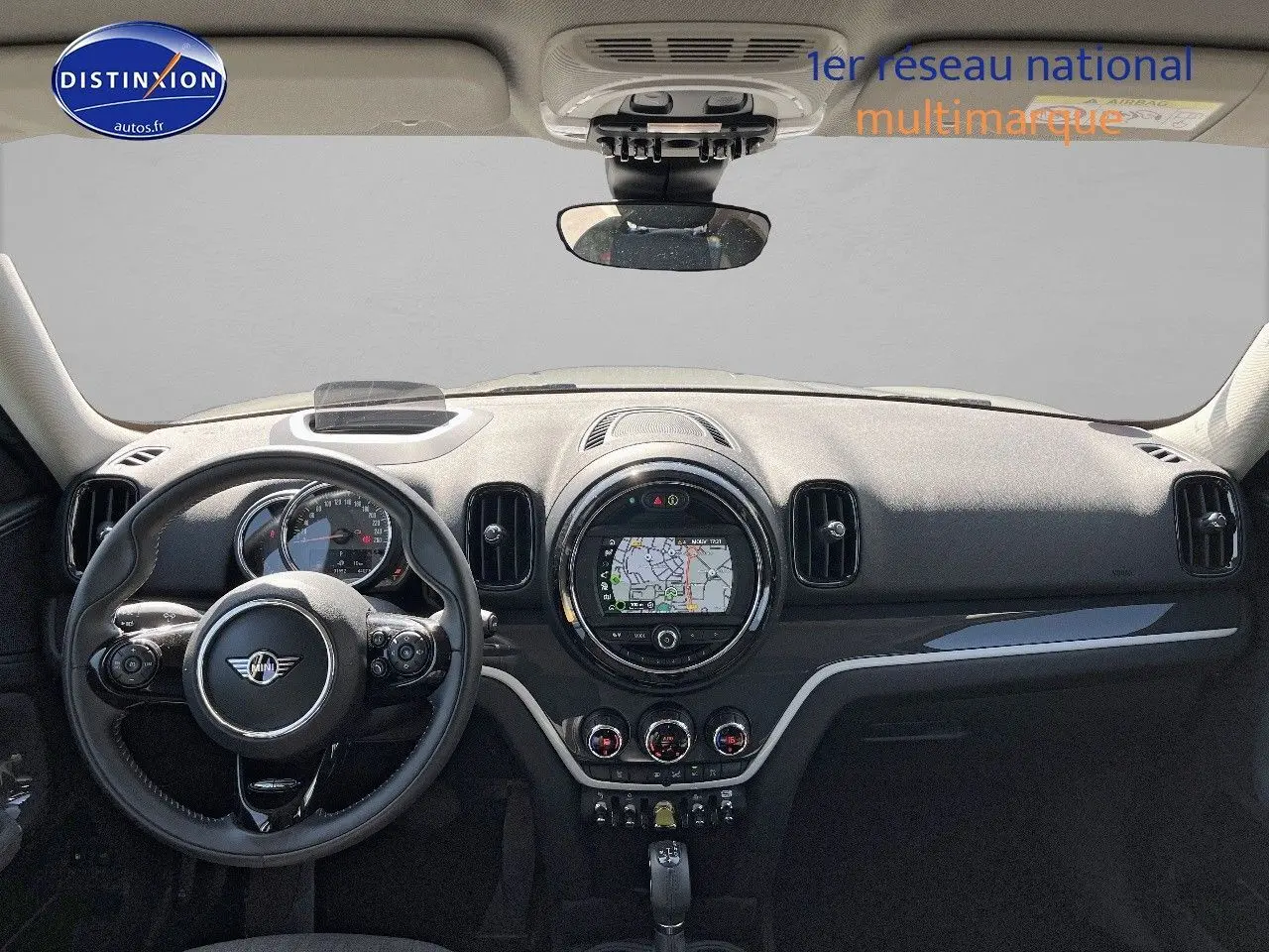 Vue frontale intérieure du tableau de bord noir du MINI Countryman Cooper SE avec écran GPS circulaire et volant multifonction.