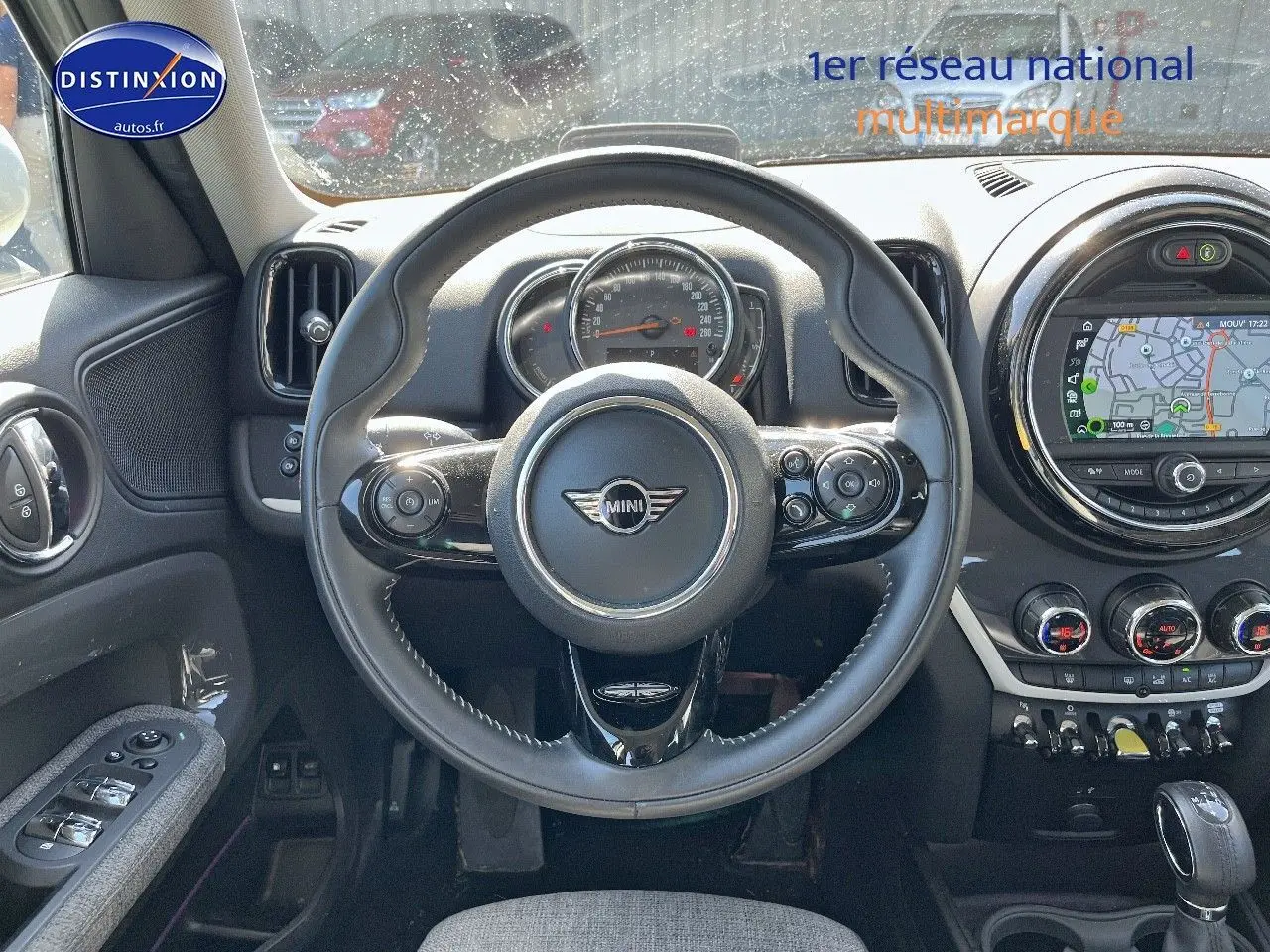Vue intérieure centrée sur le volant cuir multifonction d'une MINI Countryman avec écran GPS et commandes au volant.