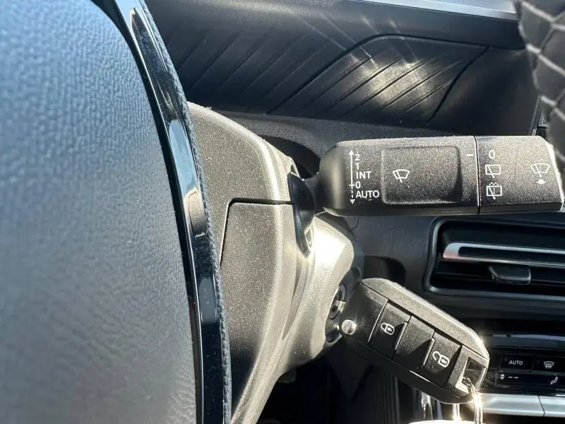 Gros plan sur la commande d’essuie-glace et clé insérée dans le contact d’une Citroën C3 noire, intérieur côté gauche.