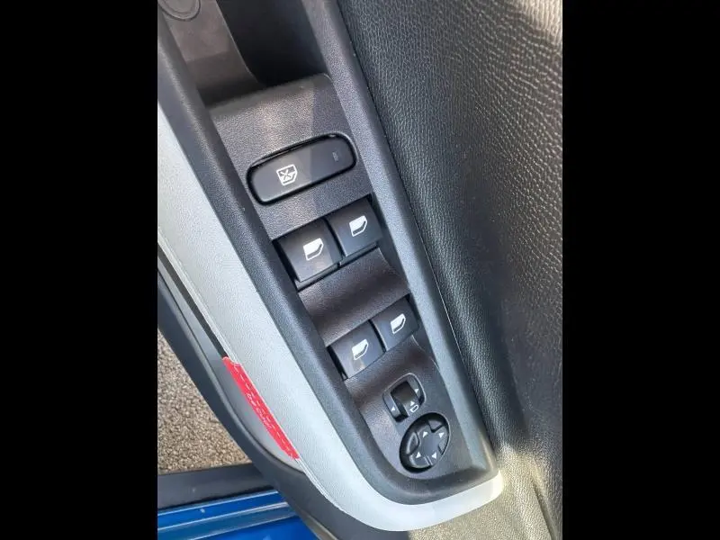 Gros plan sur les commandes des vitres et rétroviseurs côté conducteur d'une Citroën C3 noire 2025, intérieur noir.