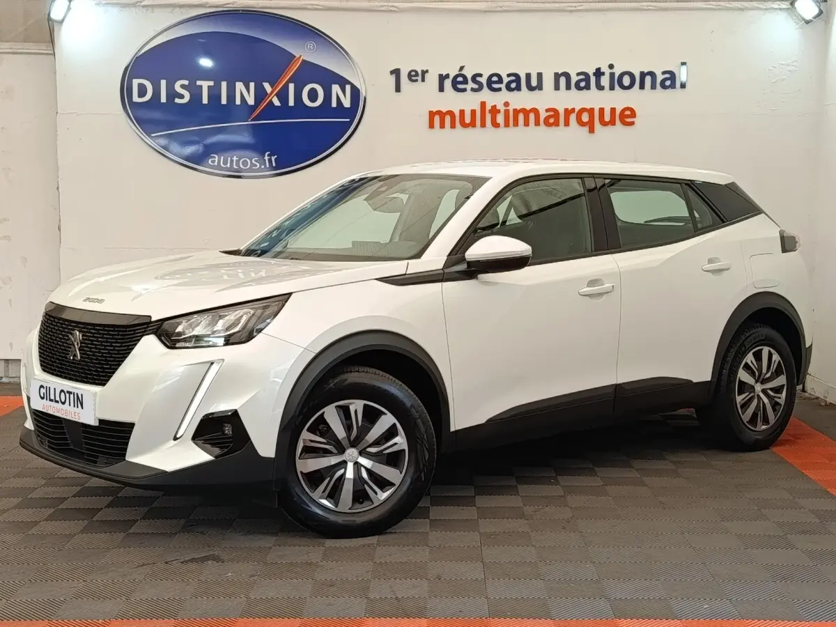 Peugeot 2008 blanc en 3/4 avant droit, avec calandre noire et jantes alliage bicolores, en intérieur showroom.
