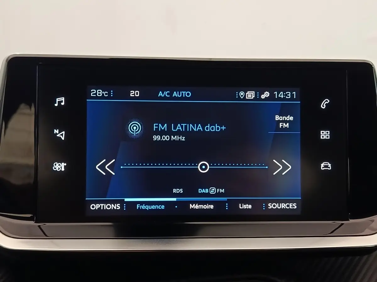 Écran tactile central du tableau de bord du Peugeot 2008 blanc, affichant la radio FM Latina à 99 MHz.