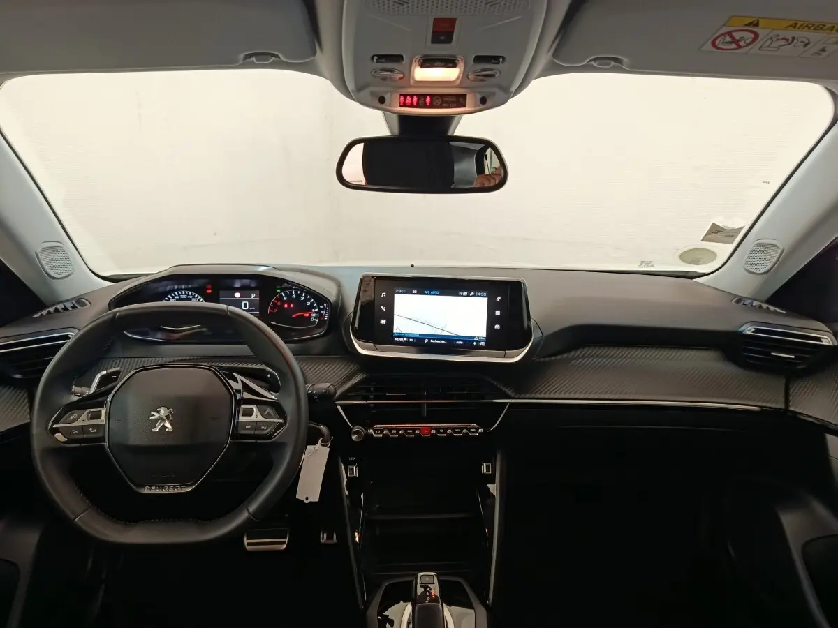 Vue intérieure avant du tableau de bord noir du Peugeot 2008 2021 avec volant cuir multifonctions et écran tactile central.