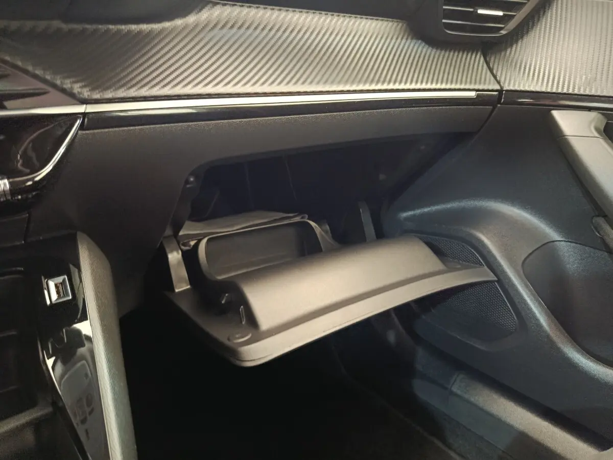Intérieur de la Peugeot 2008 2021, vue du coffre à gants ouvert côté passager avec finition noire et détails carbone.