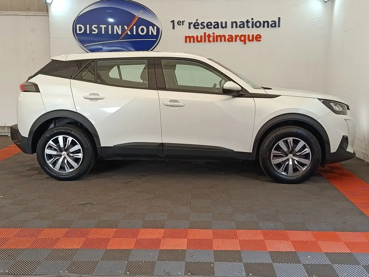 Peugeot 2008 blanc vue de profil côté gauche, avec jantes alliage et détails noirs contrastants.