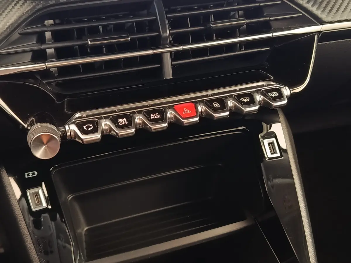 Gros plan sur la console centrale noire du Peugeot 2008 avec boutons de commande et ports USB visibles.