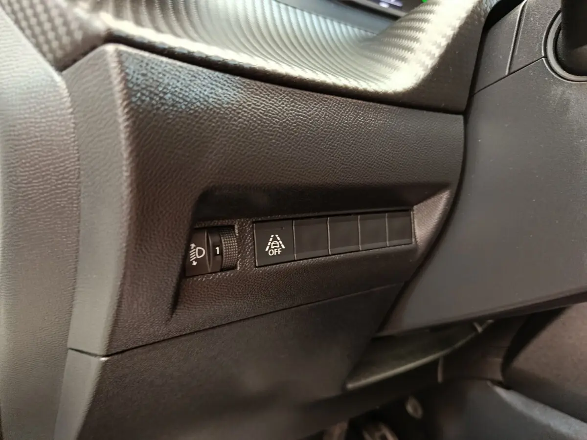 Détail intérieur côté gauche du tableau de bord noir du Peugeot 2008 avec commandes d’éclairage et d’aide à la conduite.