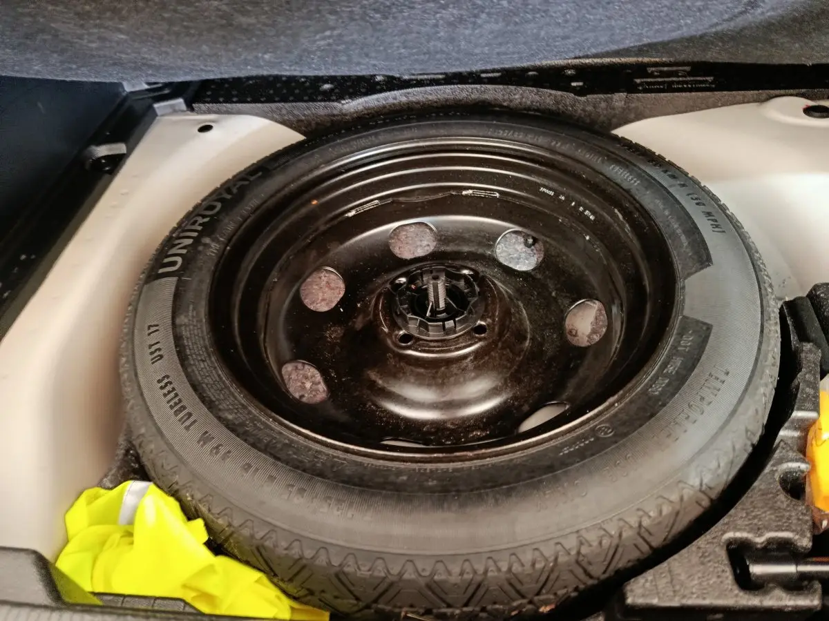 Gros plan sur la roue de secours noire dans le coffre blanc d’un Peugeot 2008 BlueHDi 130 de 2021.