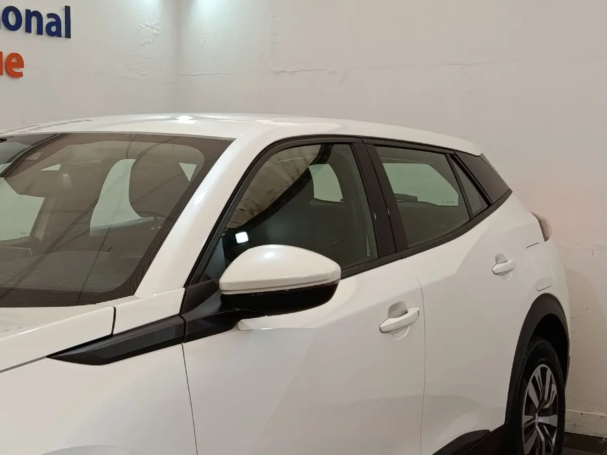 Vue de profil côté gauche d'un Peugeot 2008 blanc avec rétroviseur électrique et jantes alliage.