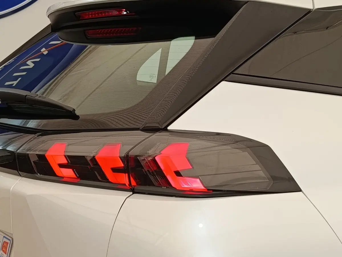 Feu arrière droit allumé d’un Peugeot 2008 blanc, vue rapprochée sur la partie arrière et le toit noir.