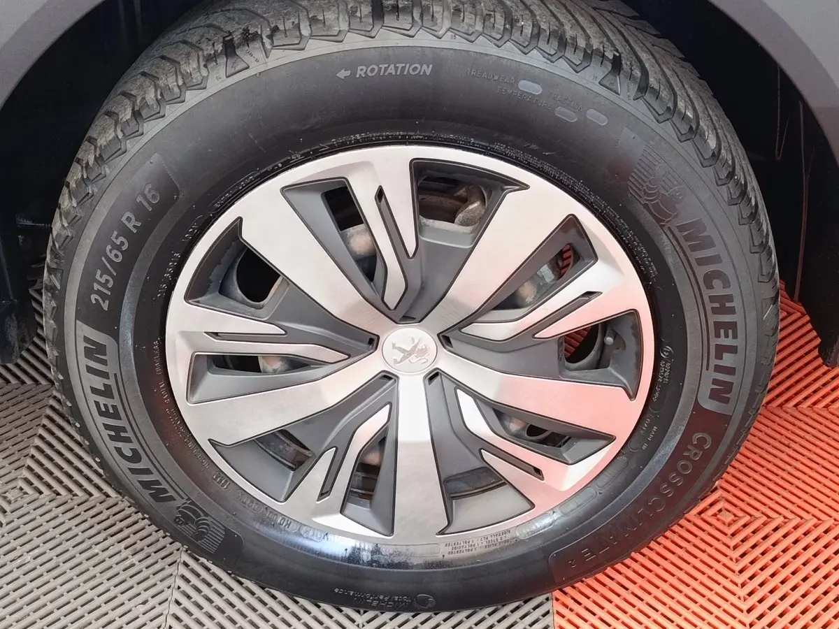 Gros plan sur la roue avant droite d’un Peugeot 2008 blanc, avec jante alliage et pneu Michelin.