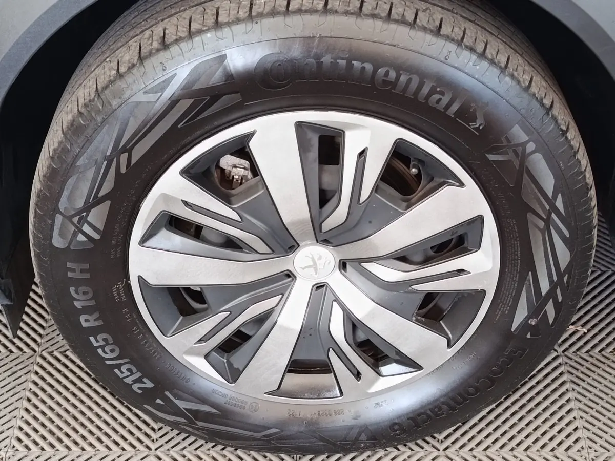 Gros plan sur la roue avant gauche d'un Peugeot 2008 blanc, jante alliage à design moderne et pneu Continental.