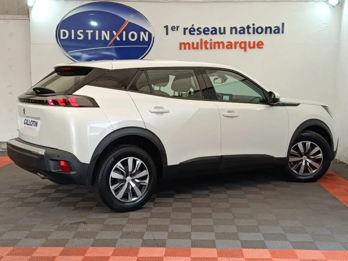 Peugeot 2008 blanc vue de profil côté droit en intérieur avec jantes alliage et toit noir contrasté.