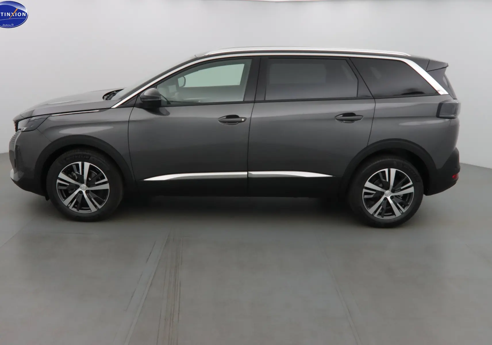 Profil latéral droit d'un Peugeot 5008 gris platinium métal avec jantes alliage bicolores et vitres teintées.