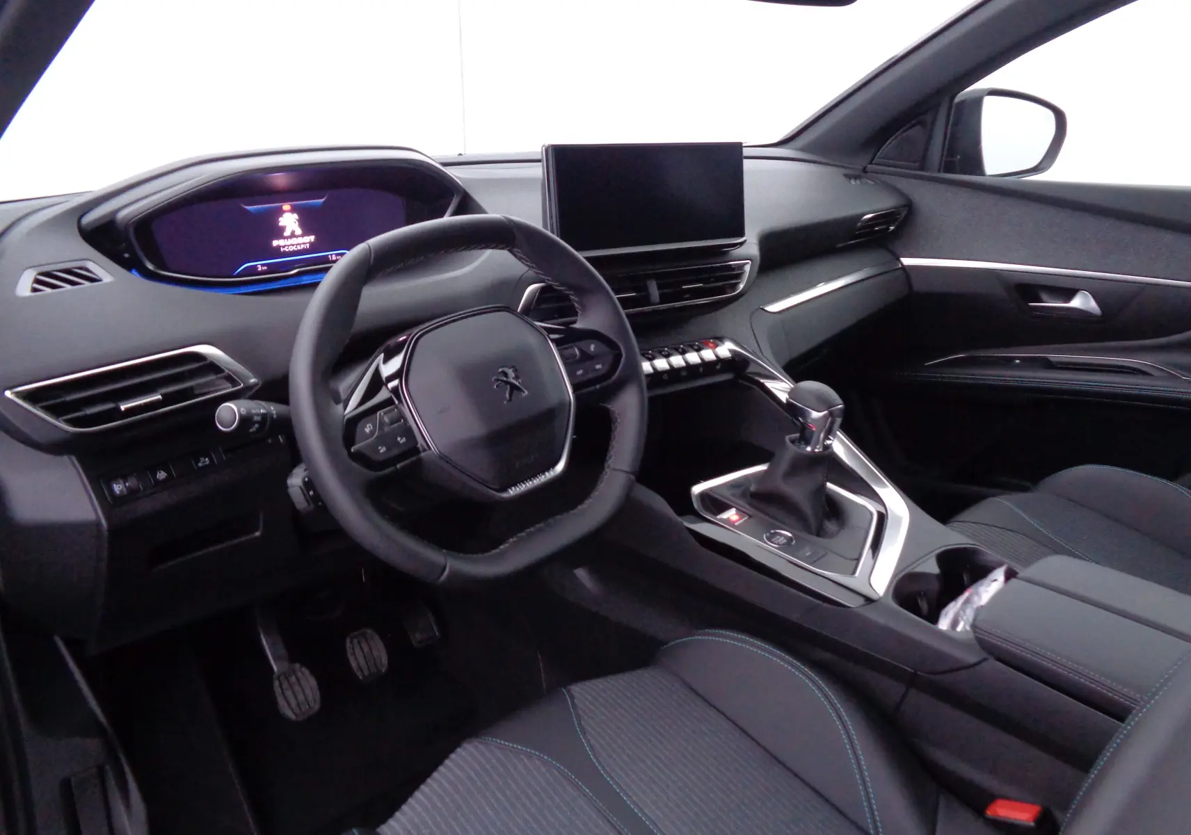 Intérieur de la Peugeot 5008 2023, vue côté conducteur, tableau de bord noir avec écran tactile et levier de vitesse manuel.