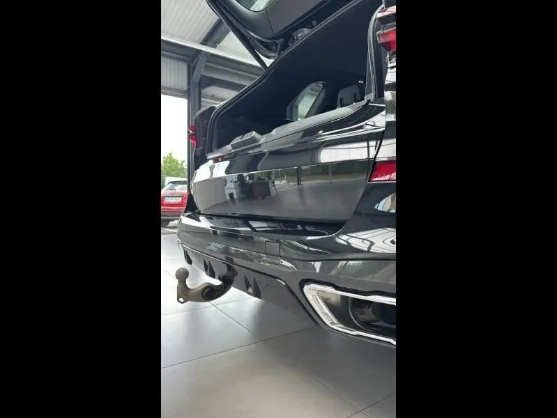Vue rapprochée arrière droite du BMW X5 xDrive50e noir avec coffre ouvert et attelage visible en concession.