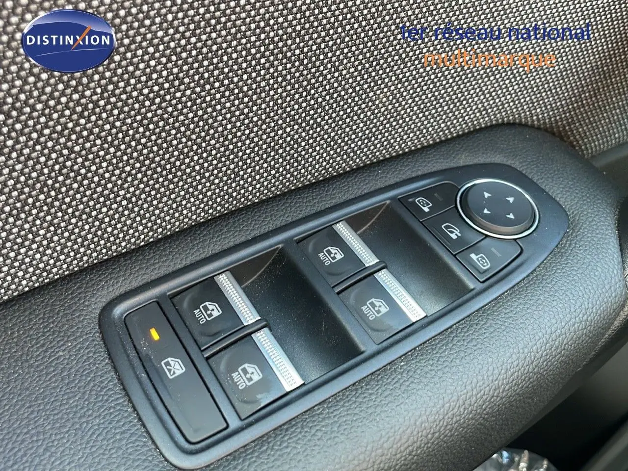 Gros plan sur les commandes des vitres électriques et rétroviseurs du côté conducteur d'un Renault Captur noir étoile métal toit gris.