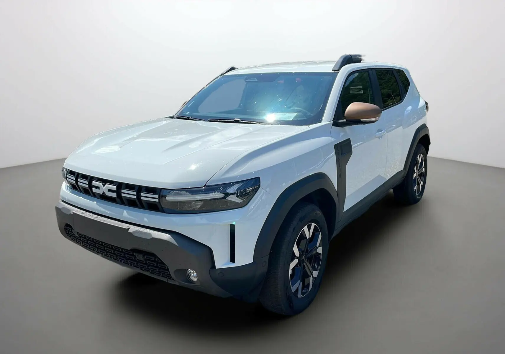 Dacia Duster 2025 blanc en 3/4 avant droit avec détails noirs et rétroviseurs couleur bronze.