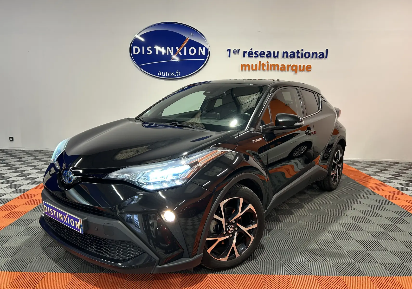 Toyota C-HR Hybride noir métal en 3/4 avant droit, phares LED allumés et jantes bi-ton distinctives.