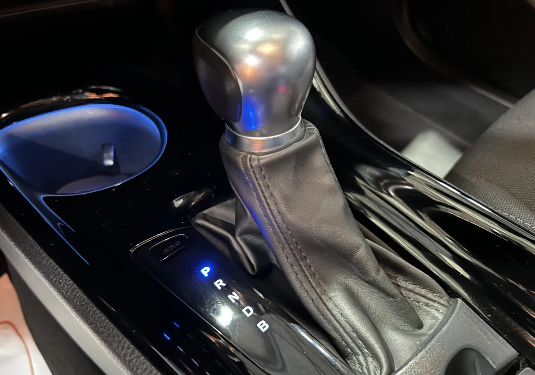 Le levier de vitesses automatique en cuir noir du Toyota C-HR Hybride 122h Edition 2WD vu en gros plan intérieur.