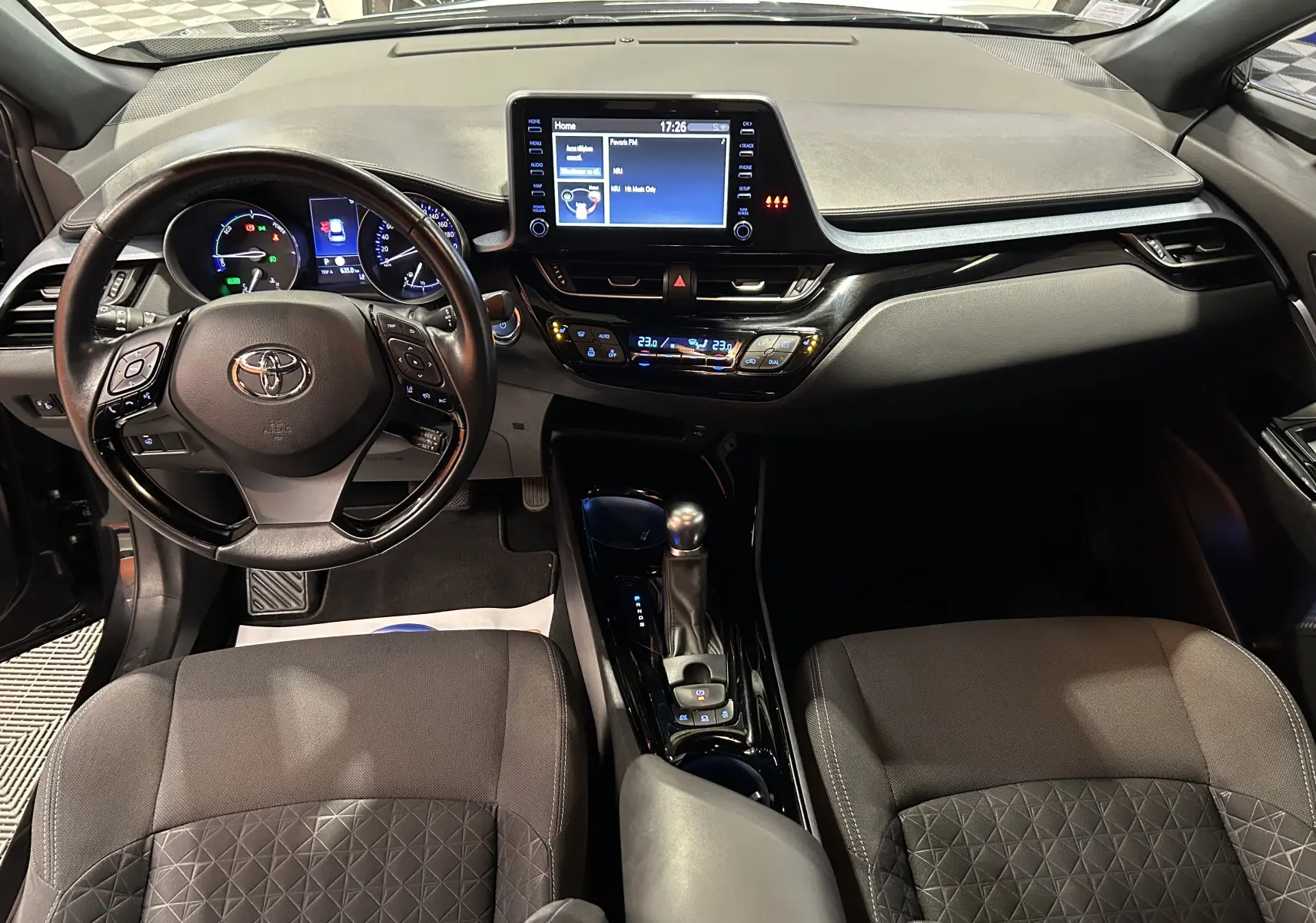 Vue intérieure avant du Toyota C-HR Hybride 122h Edition 2WD avec tableau de bord noir et écran tactile central.