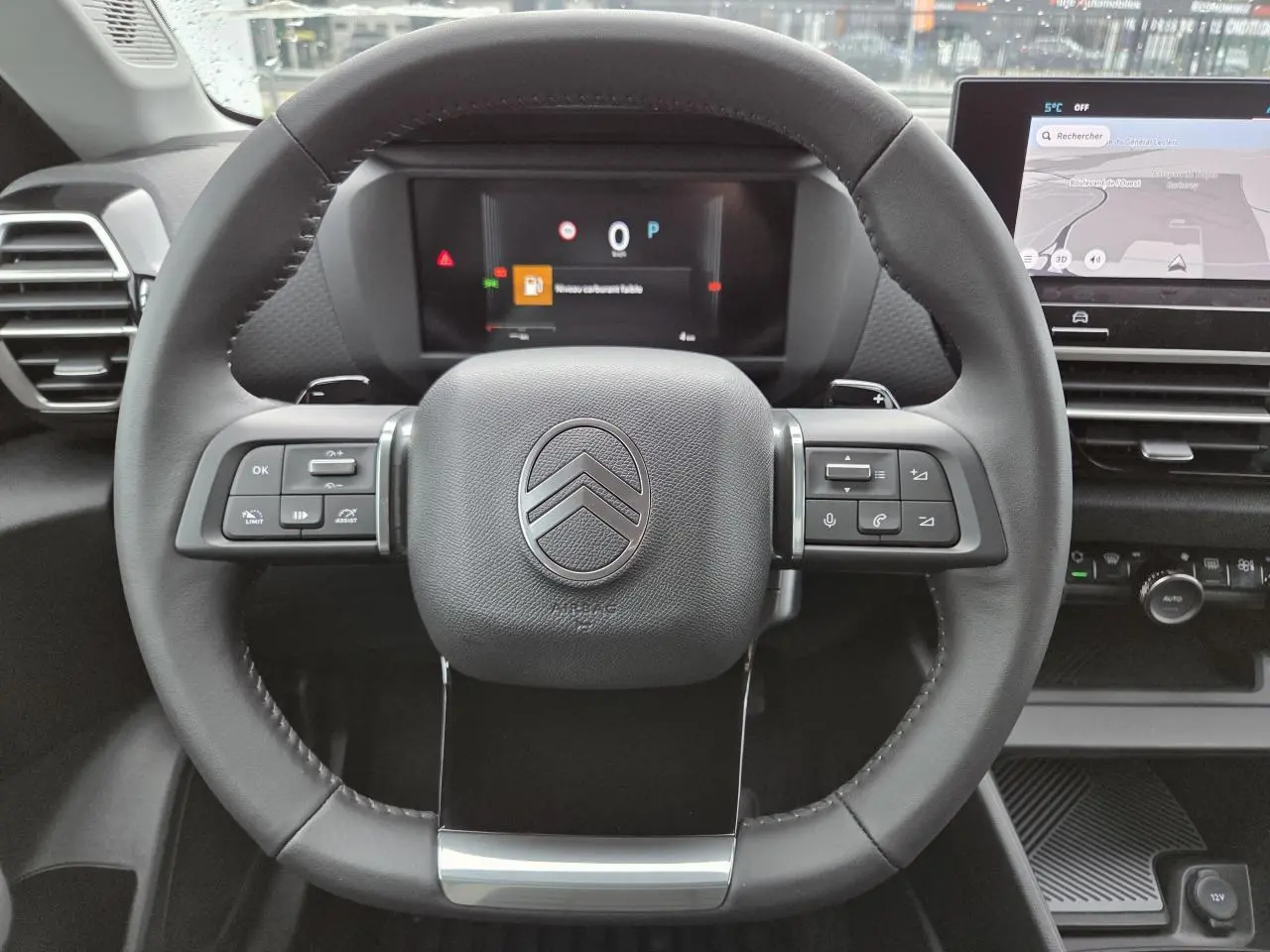 Volant en cuir noir avec commandes intégrées et tableau de bord numérique d'une Citroën C4 hybride 2025 vue de face.
