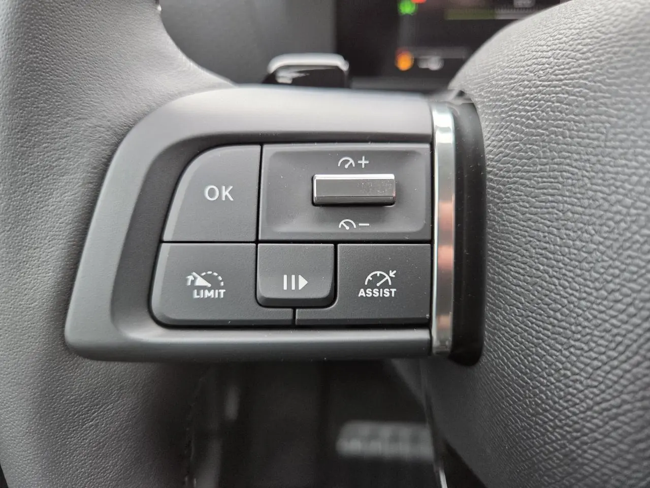 Gros plan sur les commandes au volant à gauche du Citroën C4 III blanc Okenite avec toit noir, boutons de régulateur et assistances.