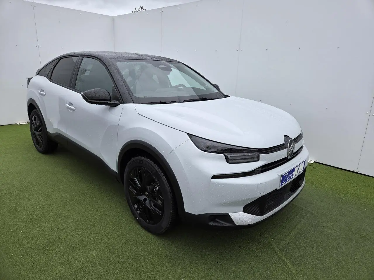 Citroën C4 III hybride blanc Okenite avec toit noir, vue 3/4 avant droit, jantes alliage noires et feux LED fins.