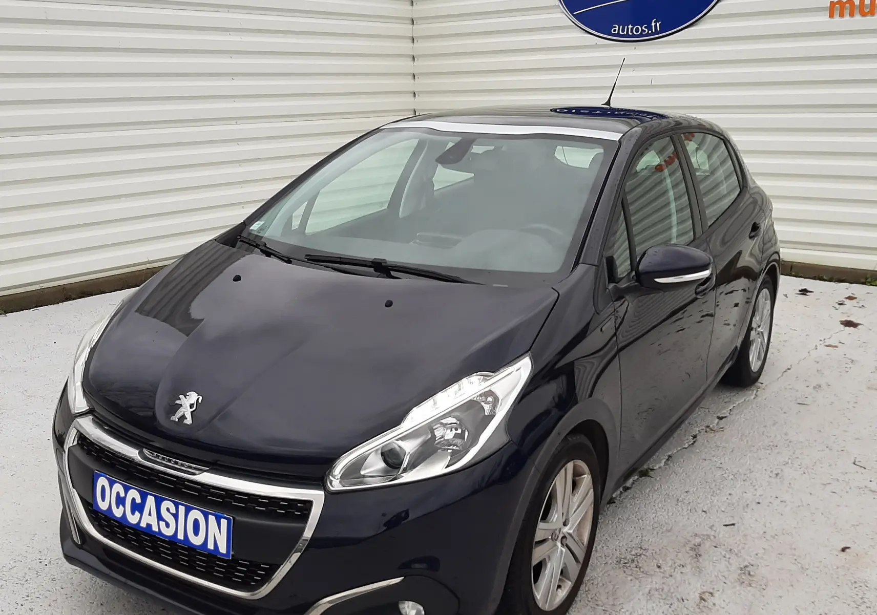Peugeot 208 bleu nuit vue 3/4 avant droit, avec calandre chromée et jantes alliage 16 pouces.