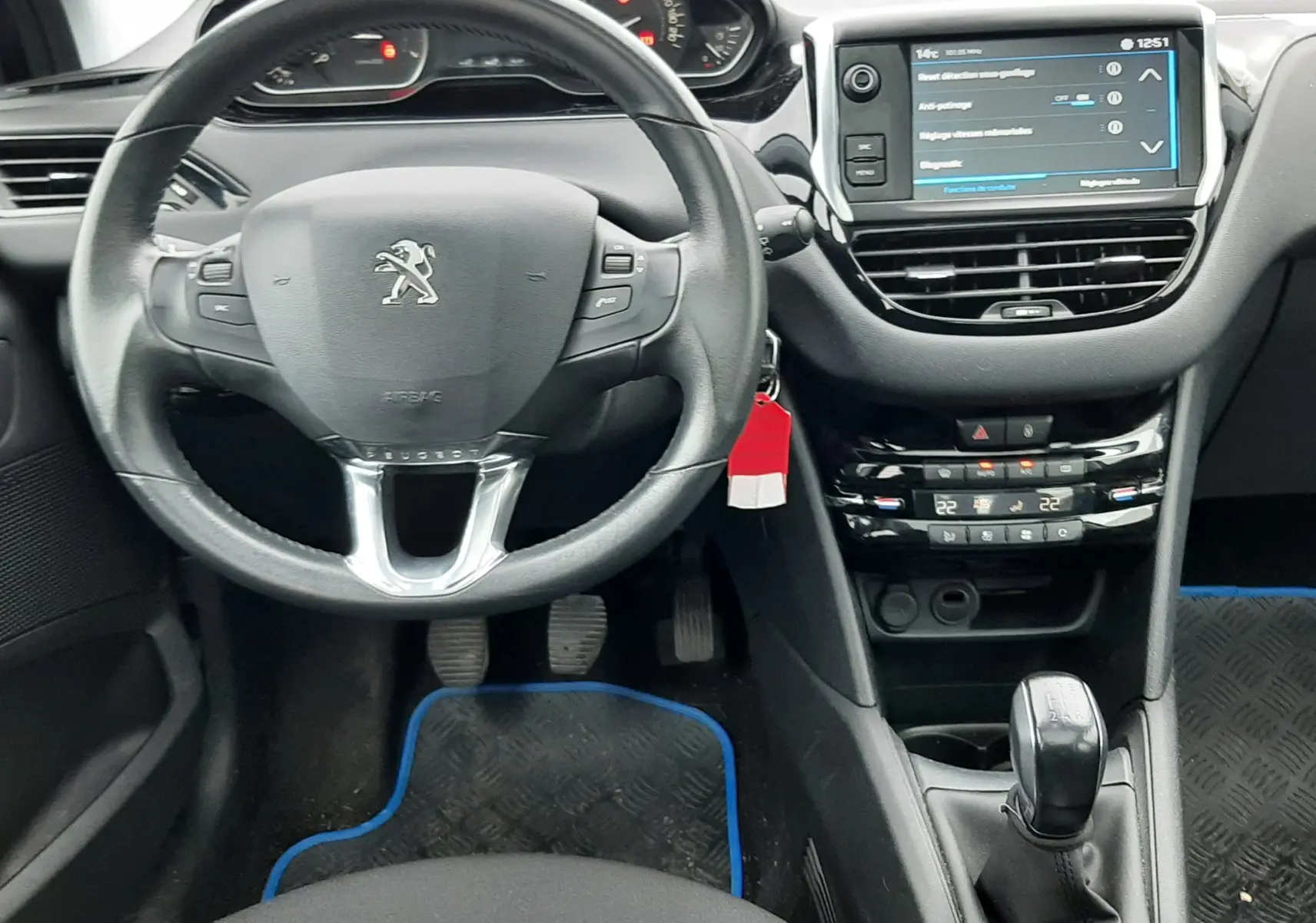 Vue intérieure avant du tableau de bord de la Peugeot 208 bleu nuit, avec volant multifonction et écran tactile central.