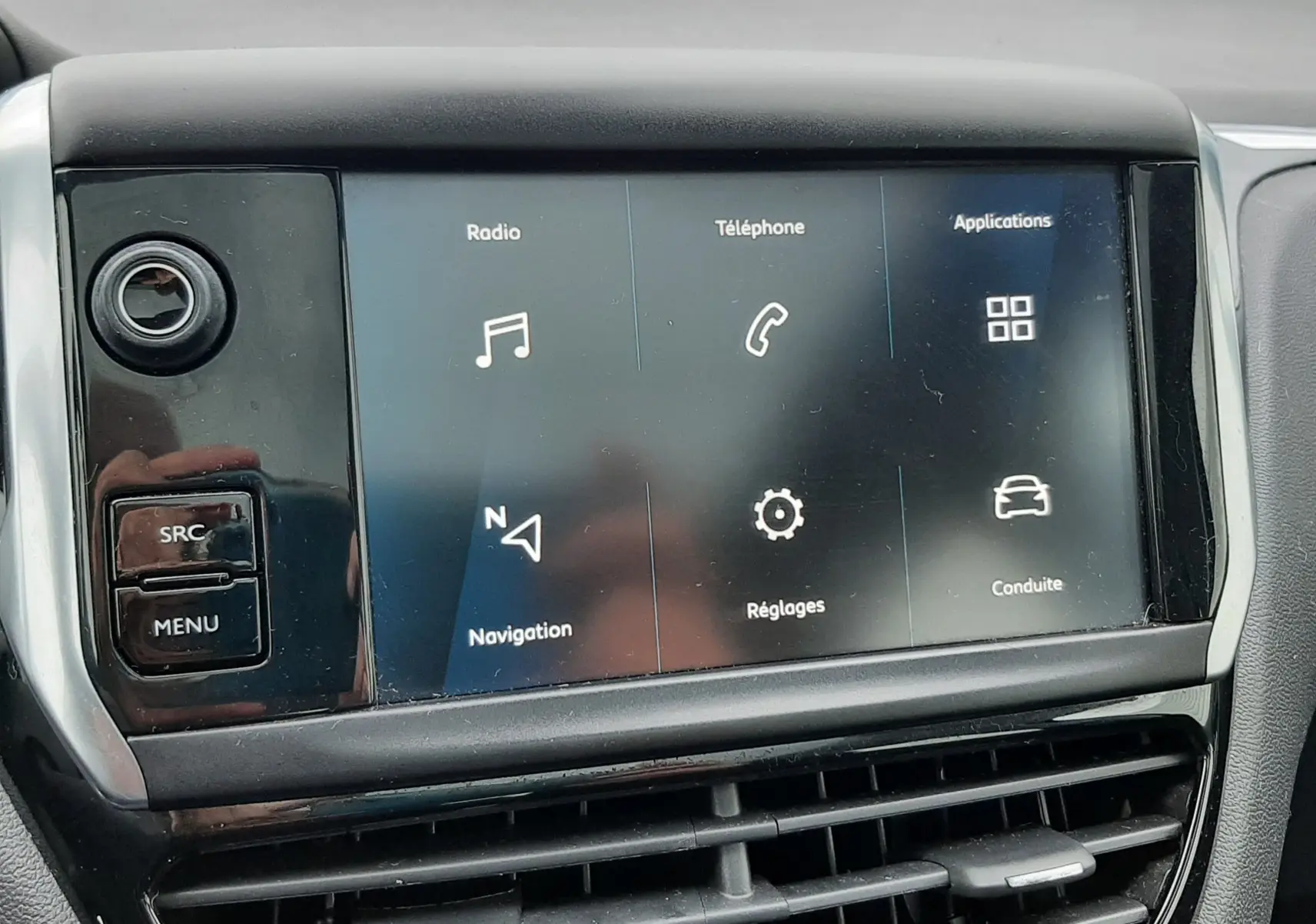 Écran tactile central du tableau de bord de la Peugeot 208 bleu nuit, affichant les menus radio, téléphone et navigation.