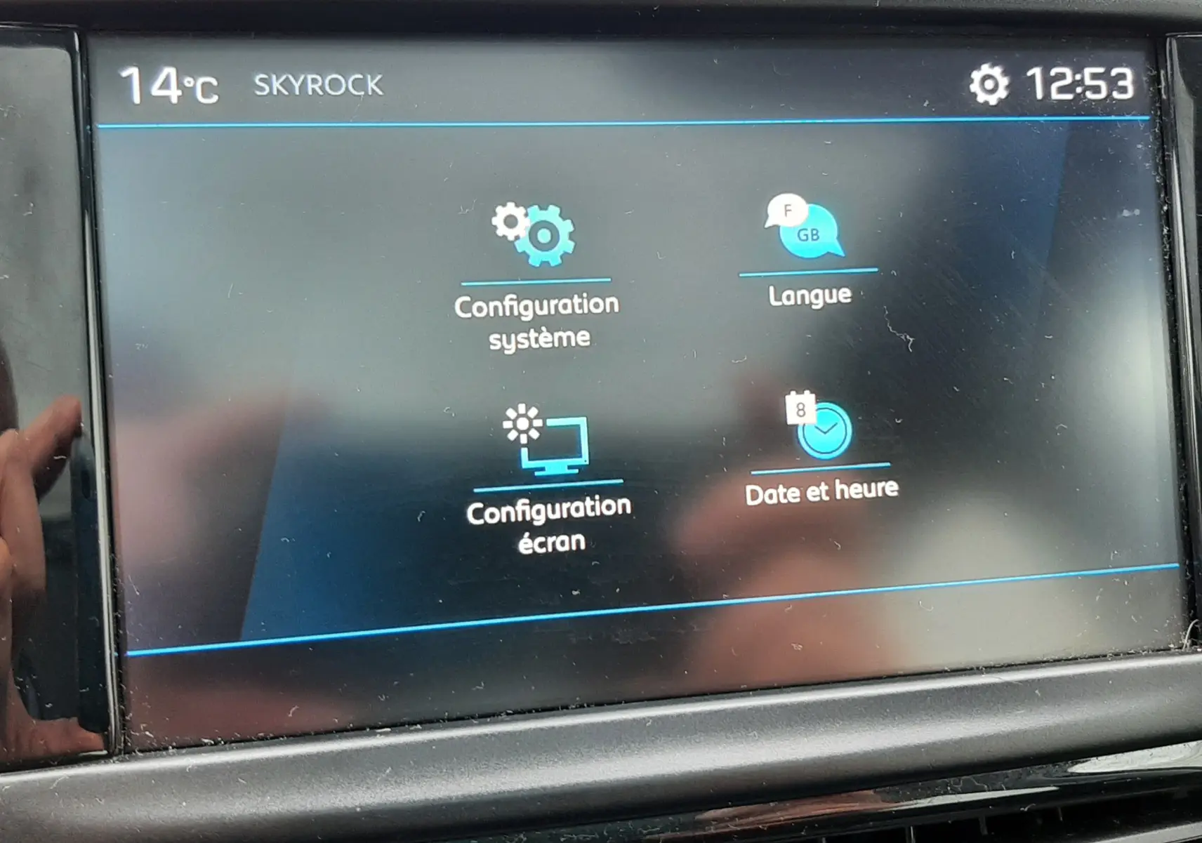 Écran tactile central de la Peugeot 208 bleu nuit 2019 affichant les réglages système, langue, écran et date.