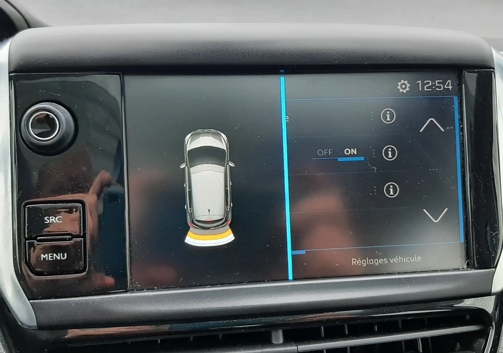 Écran central de la Peugeot 208 2019 montrant l'alerte de proximité arrière avec interface tactile et commandes à gauche.