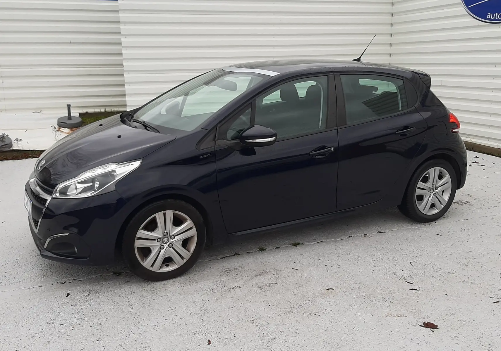 Peugeot 208 bleu nuit vue de profil côté gauche, compacte cinq portes avec jantes alliage et feux avant LED.