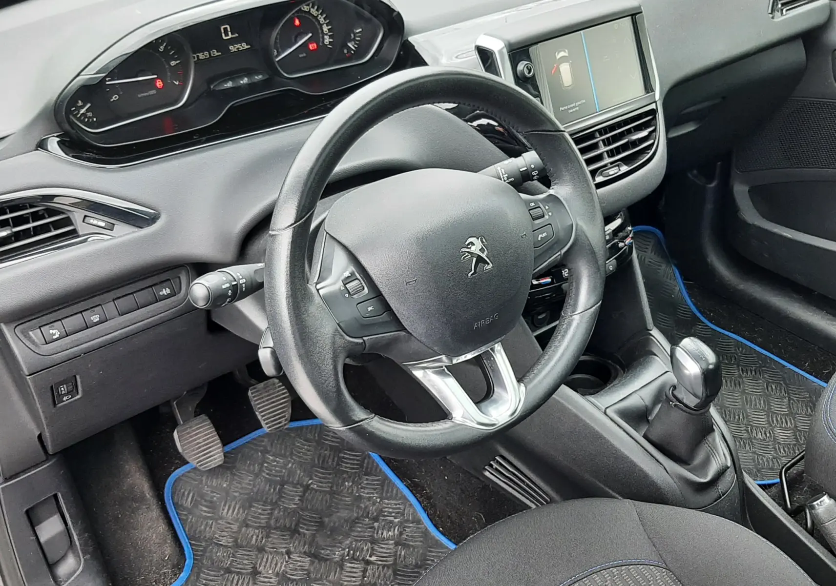 Intérieur avant droit de la Peugeot 208 bleu nuit 2019, volant compact, tableau de bord digital et console centrale avec boîte manuelle.