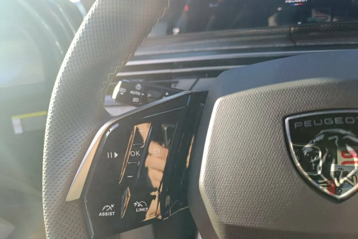 Gros plan sur le volant cuir multifonctions du Peugeot 3008 Hybrid 2025 avec logo et commandes intégrées.