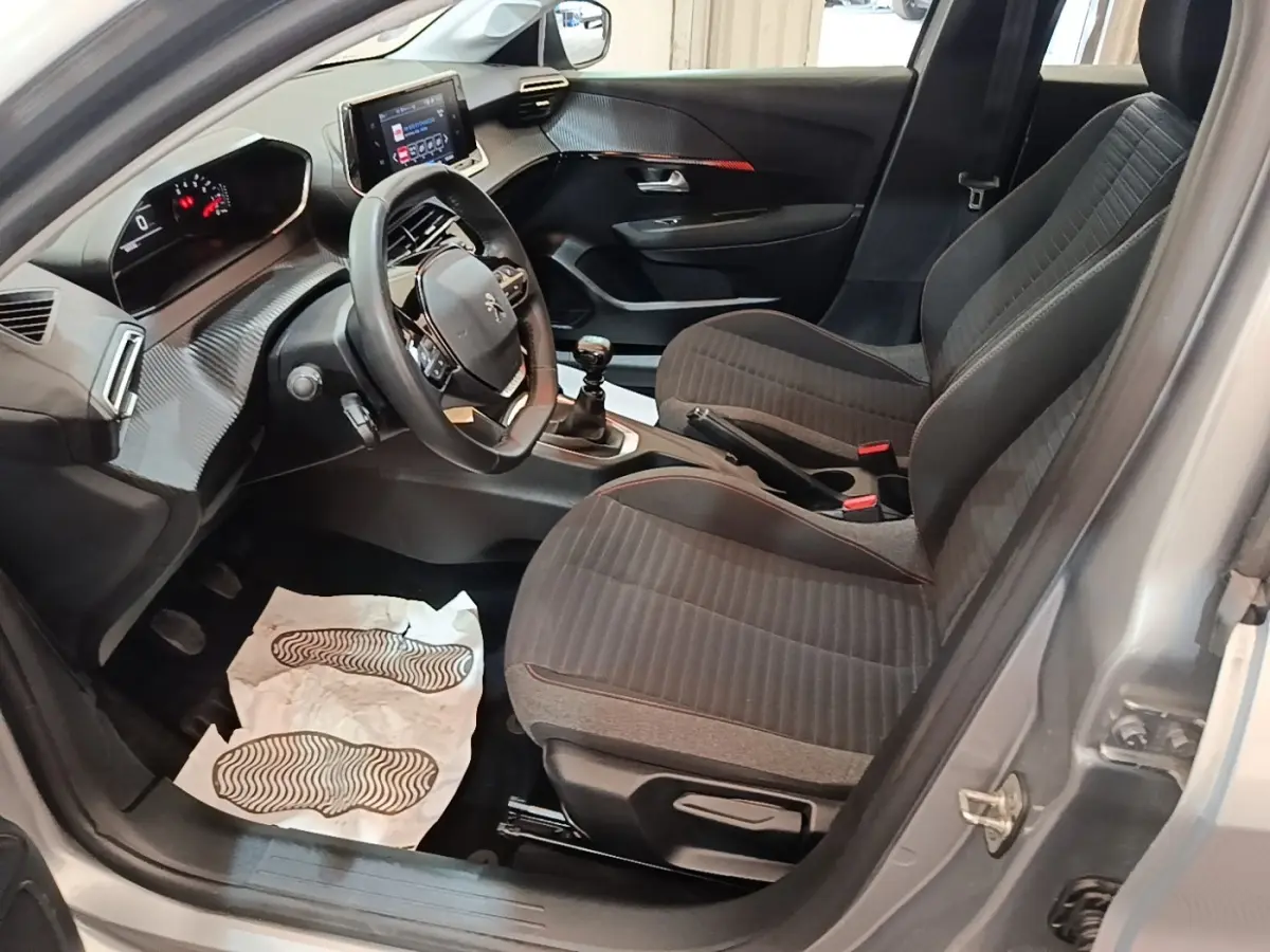 Vue intérieure côté conducteur de la Peugeot 208 gris clair, volant cuir multifonctions et tableau de bord digital.