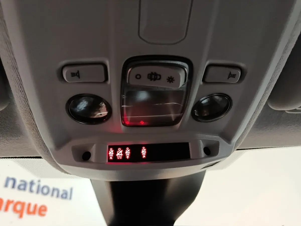 Vue en gros plan du plafonnier gris clair de la Peugeot 208 PureTech 100 avec voyants de ceinture allumés.