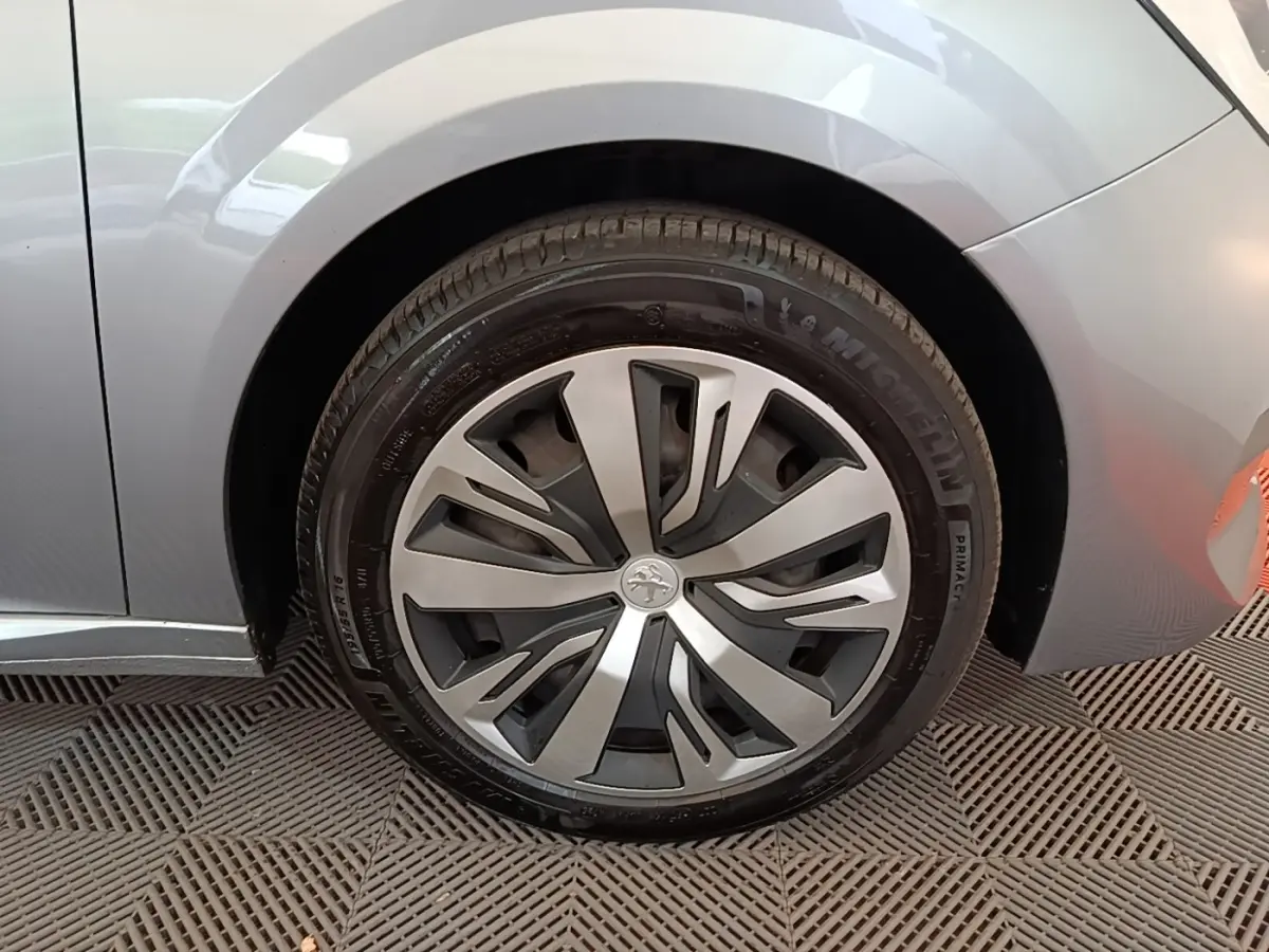 Gros plan sur la roue avant droite gris clair d'une Peugeot 208 2023 avec jante alliage au design moderne.
