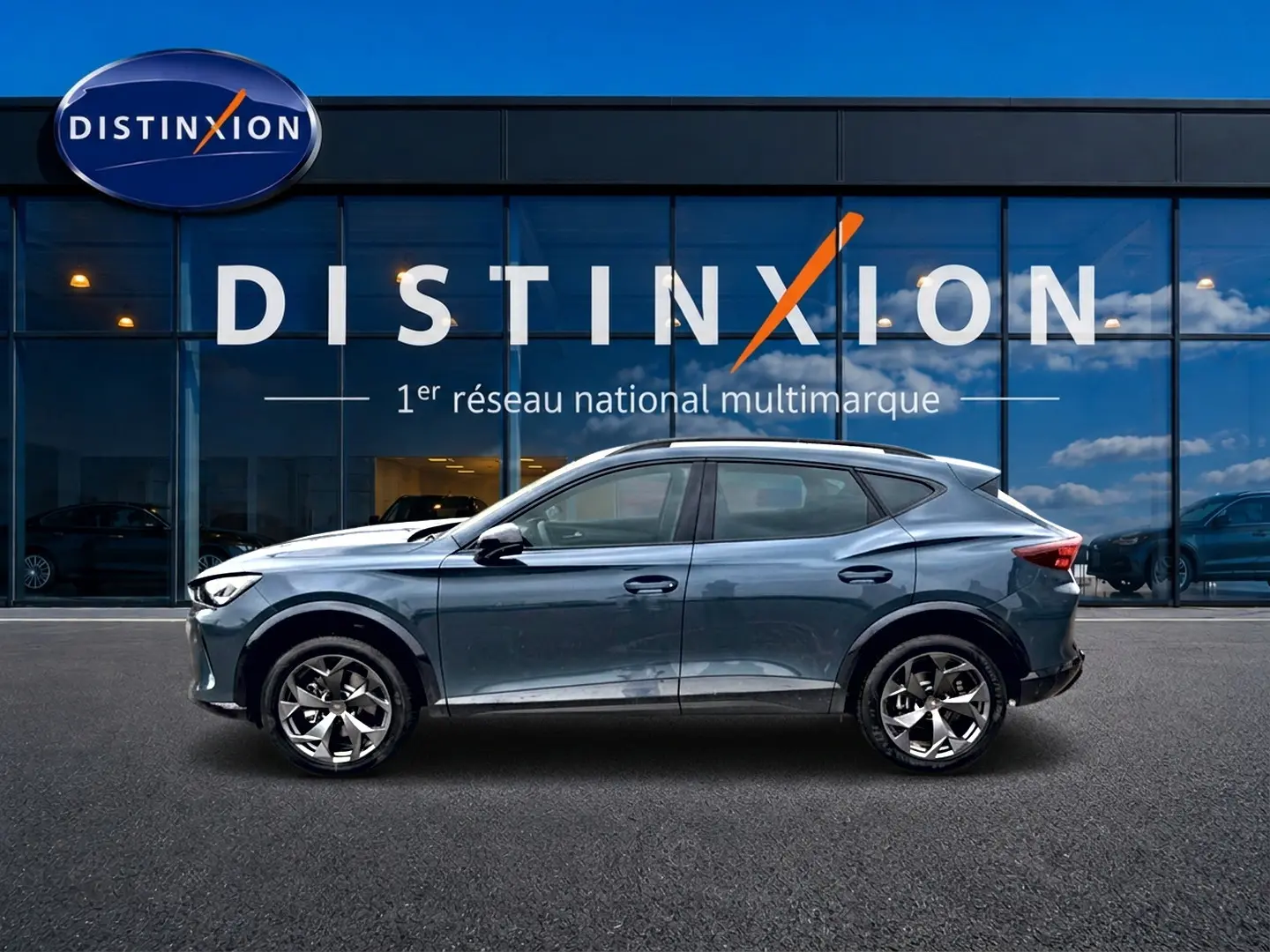 Vue de profil côté gauche d'une CUPRA Formentor 1.5 etsi hybrid 2026 en bleu fjord devant une vitrine Distinxion.