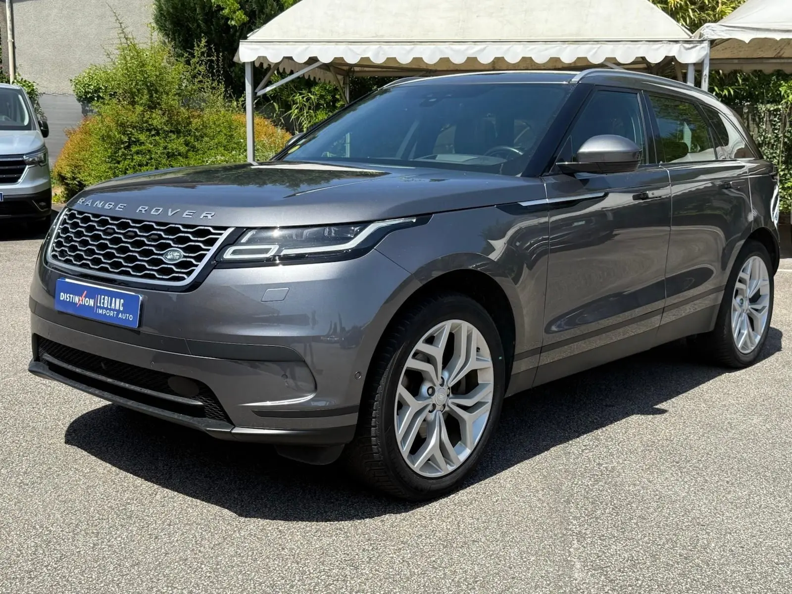 Range Rover Velar gris en vue 3/4 avant droit, avec calandre distinctive et jantes alliage modernes.