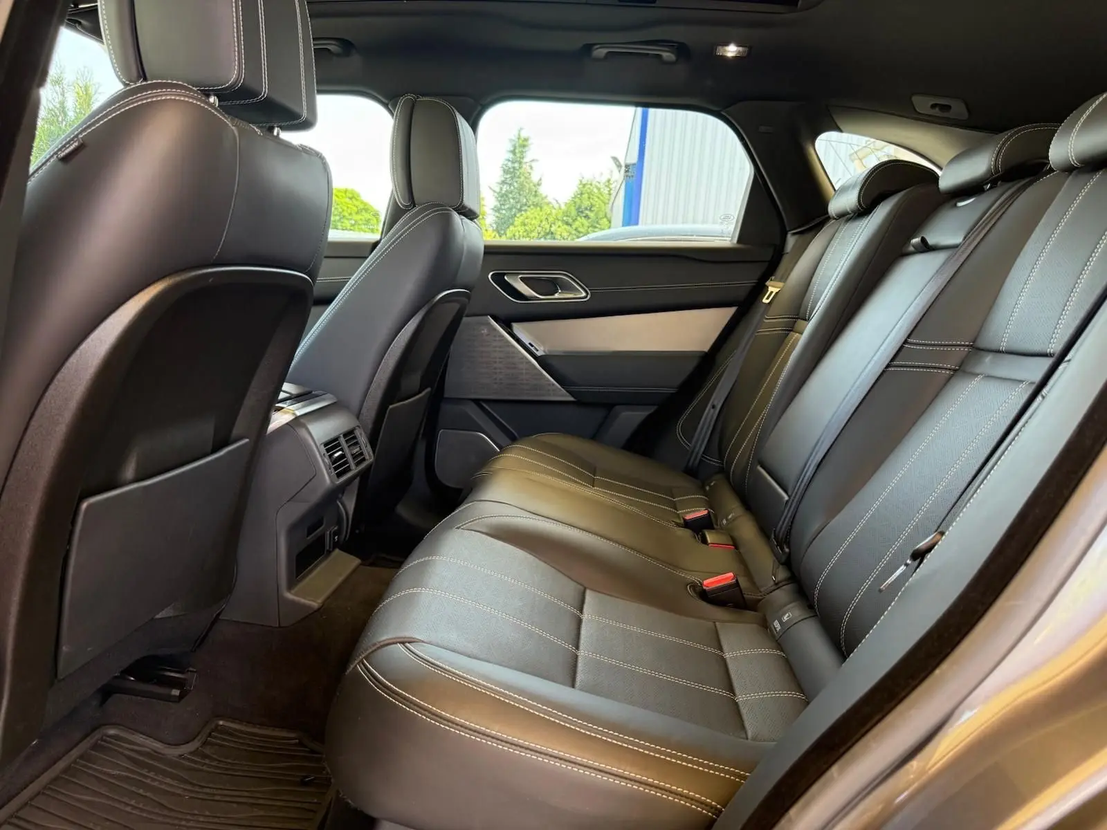 Vue latérale intérieure des sièges arrière en cuir noir avec surpiqûres blanches du Range Rover Velar gris 2019.